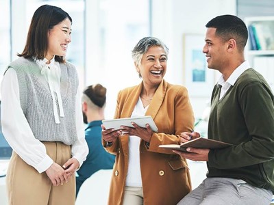 Employees smiling sat down having a talk near a desk