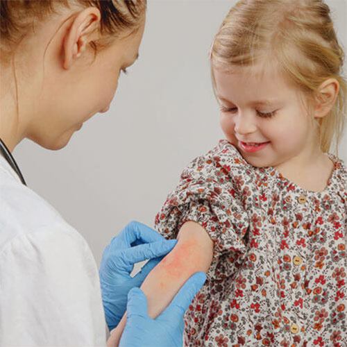 Health professional investigating a rash on child's arm